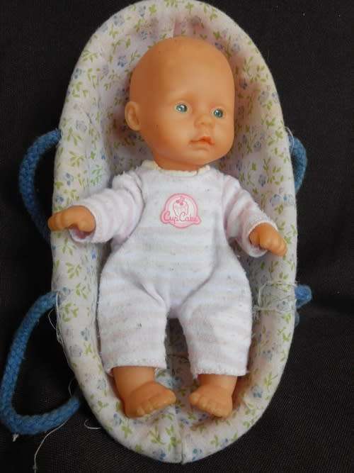 small soft bodied Simba doll in plastic carry basket