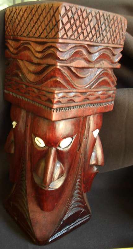 well made wooden statue in hard wood carved with heads with cowrie shell eyes