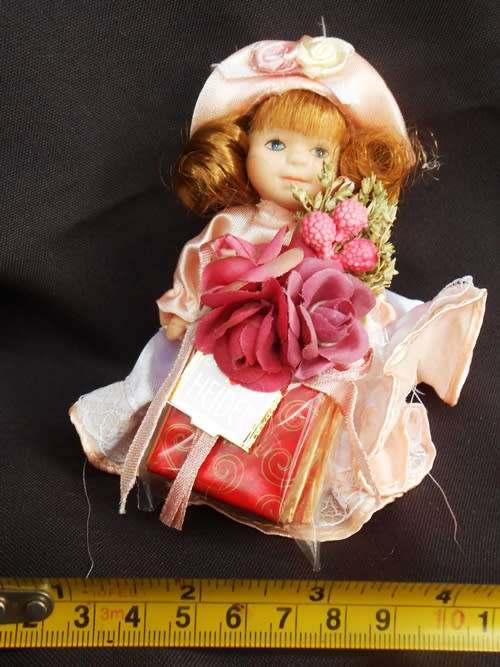 collectable small porcelain doll, Heidel, bearing flowers and a gift