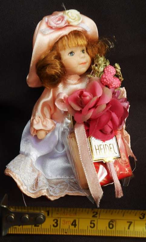 collectable small porcelain doll, Heidel, bearing flowers and a gift