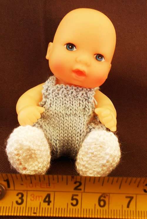 collectable small baby doll in sitting position in hand knitted outfit