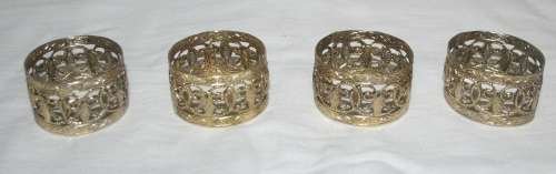A COLLECTION OF FOUR GOLD COLOR METAL SERVIETTE RINGS
