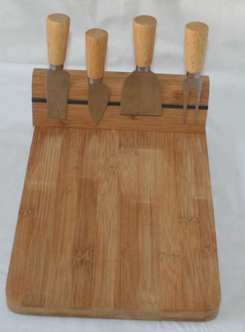 A EXQUISITE WOODEN CHEESE BOARD WITH A MAGNET BAR WERE THE CHEESE UTENSILS ARE ATTACHED