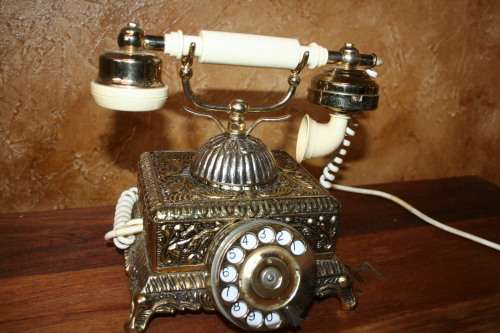AN EXQUISITE VINTAGE ROTARY DIAL TELEPHONE WITH WHITE BAKELITE HANDLE AND EMBOSSED DETAILING