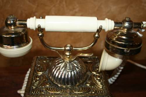 AN EXQUISITE VINTAGE ROTARY DIAL TELEPHONE WITH WHITE BAKELITE HANDLE AND EMBOSSED DETAILING