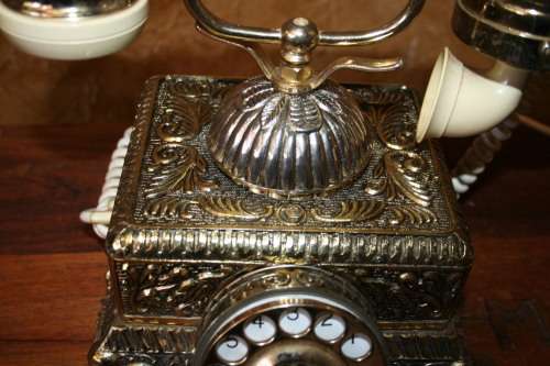 AN EXQUISITE VINTAGE ROTARY DIAL TELEPHONE WITH WHITE BAKELITE HANDLE AND EMBOSSED DETAILING