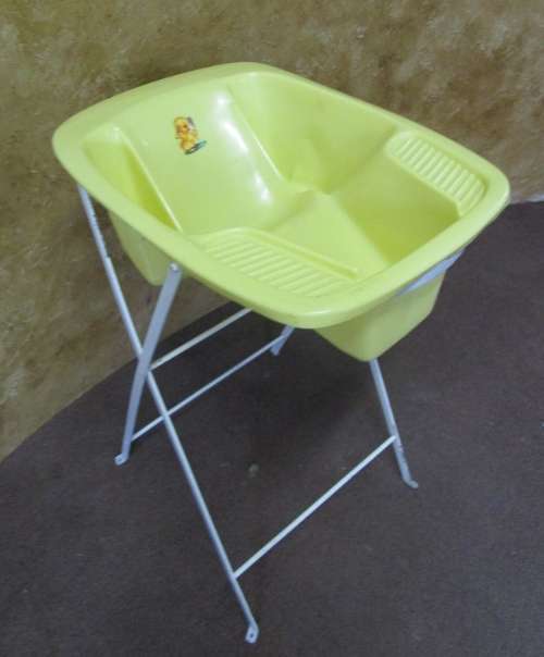 A CUTE VINTAGE BABY BATH ON A TALL METAL FOLD UP STAND