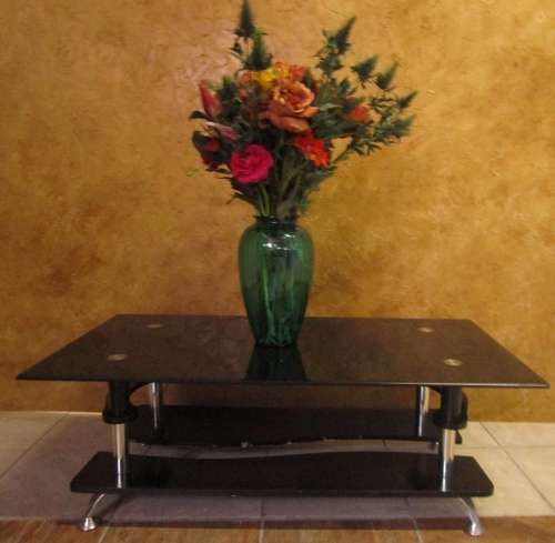 A MODERN STYLE BLACK GLASS AND STAINLESS STEEL COFFEE TABLE