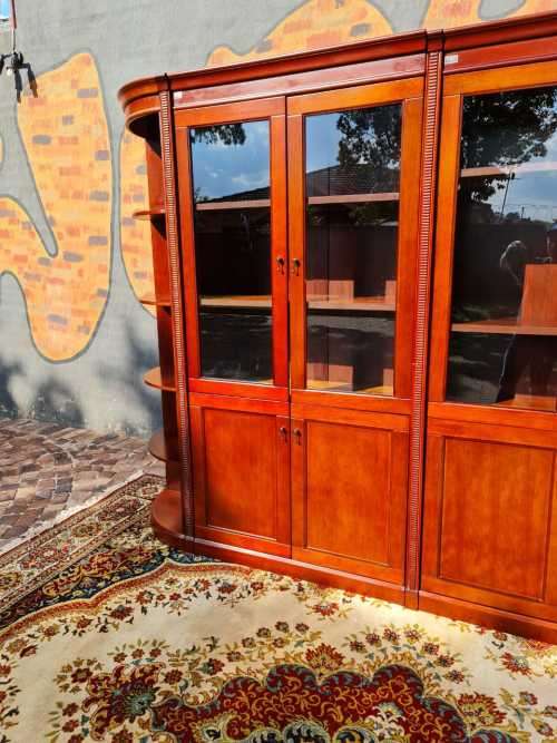 Large display cabinet with four glass doors, side shelves, and four cabinets at the bottom
