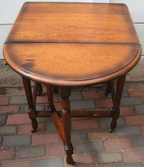 AN MAGNIFICENT DROP SIDE TABLE WITH BEAUTIFUL TURNED LEGSS RESTING ON ANTIQUE CASTER WHEELS