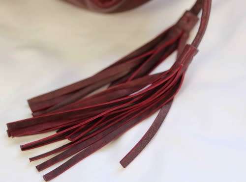 GENUINE JENNIFER LOPEZ (JLO) BURGUNDY ORIGINAL LEATHER 'HOBO' HANDBAG WITH TASSEL DETAILS.