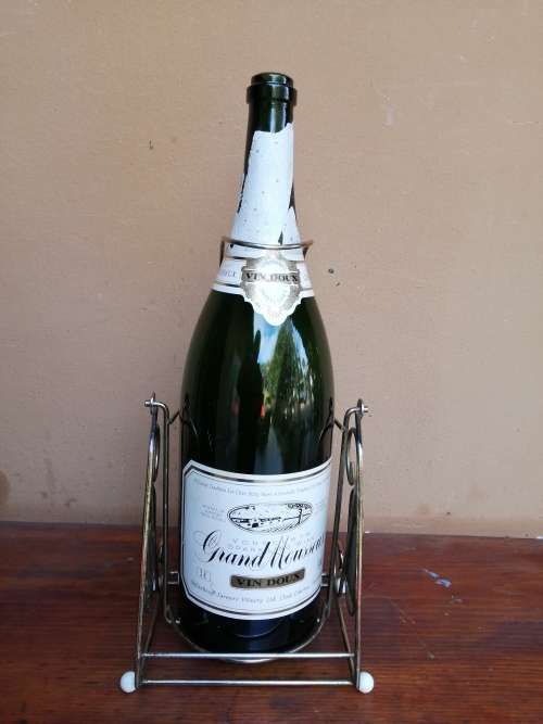 Large Grand Mousseux champagne bottle on a stand.