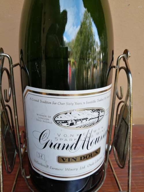 Large Grand Mousseux champagne bottle on a stand.