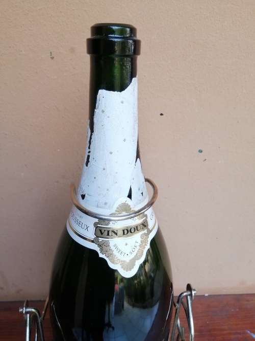 Large Grand Mousseux champagne bottle on a stand.
