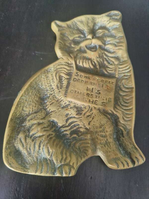 A lovely vintage brass flat cat ashtray with and embellished sign `Some people drop their H`s others