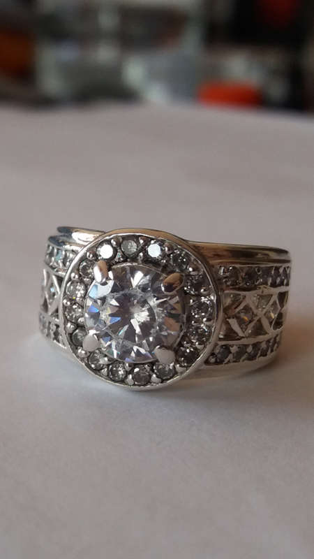 A BEAUTIFUL STERLING SILVER RING SET WITH A CENTER GEM AND GORGEOUS GEMS AROUND.