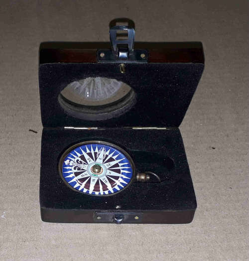 Brass compass in a solid wooden box with a floating dial.