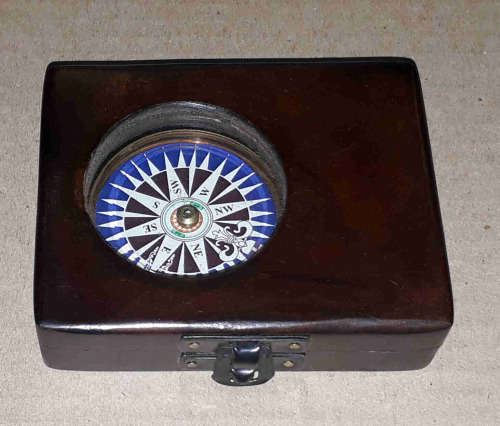 Brass compass in a solid wooden box with a floating dial.