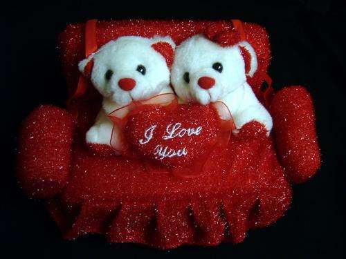 TWO LOVE BEARS SITTING ON A RED COUCH HOLDING A RED HEART