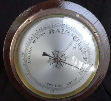 A  massive circular barometer encased in wood (probably oak {1:5kg)