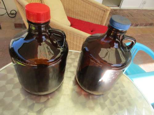 TWO BROWN GLASS DEMIJOHNS RED AND BLUE TOPS