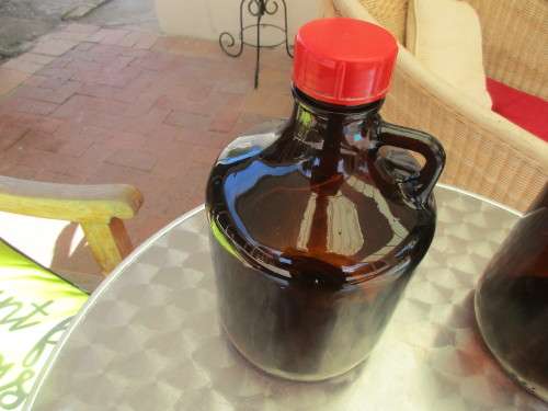 TWO BROWN GLASS DEMIJOHNS RED AND BLUE TOPS