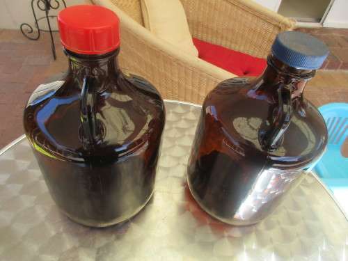TWO BROWN GLASS DEMIJOHNS RED AND BLUE TOPS
