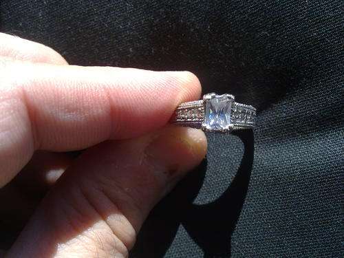 Sterling silver open ended ring with a top colourless gem and small ones on the side