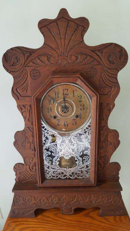 An Ansonia MANTLE CLOCK, with Arabic numerals, the shaped and carved dark stained oak case on a step