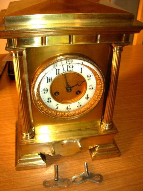 A 19thC gilt metal cased MANTLE CLOCK, with a Corinthian column to either side of the dial, the enam