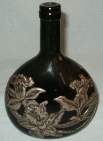 A PEWTER DECORATED GREEN GLASS BOTTLE