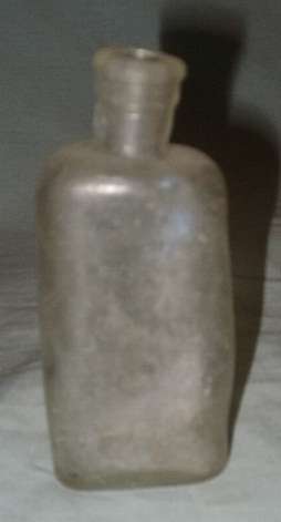 A FUNNY SHAPED OLD GLASS BOTTLE