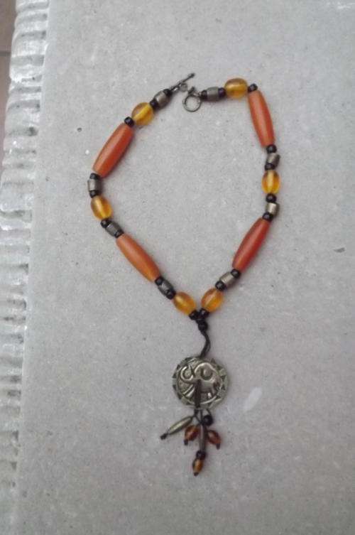 Bulky ethnic necklace.Amber colour beads and brass pendant.Good condition
