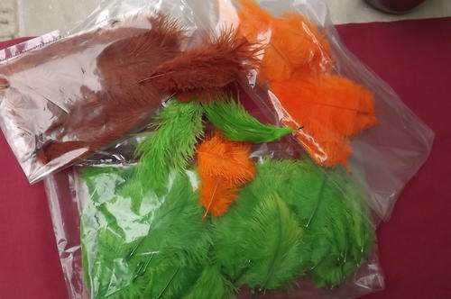 Lot of small ostrich feathers.Green,orange and brown.About 80