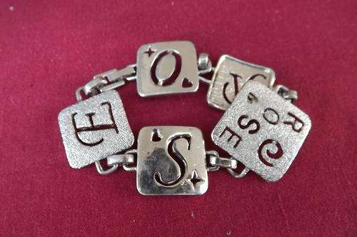 Metal bracelet with squares hooked together.The word Rose is written on it.Good condition