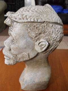 AN AFRICAN HEAD CARVED FROM STONE AND SIGNED UNDERNEATH