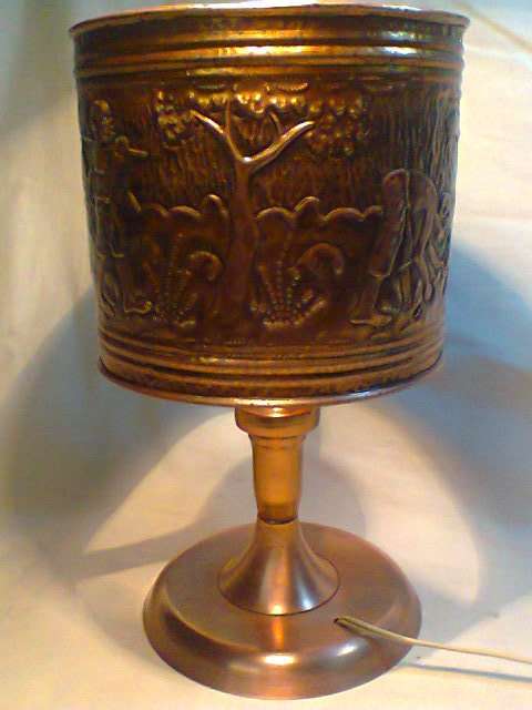 A Old Ethnic Copper Table Lamp. It has African Embossed figurines , Hut , Tree's & other scenes.