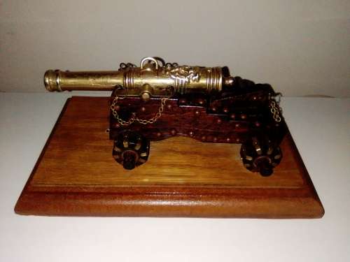 A Brass Canon with crest on Barrel, mounted on a wooden plinth with 4 feet.