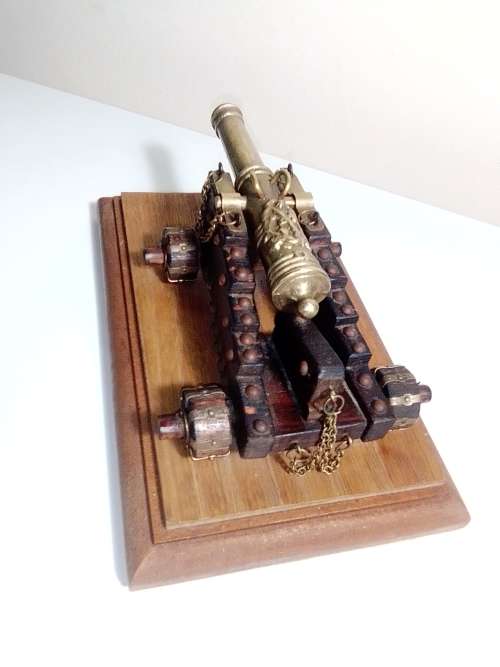 A Brass Canon with crest on Barrel, mounted on a wooden plinth with 4 feet.
