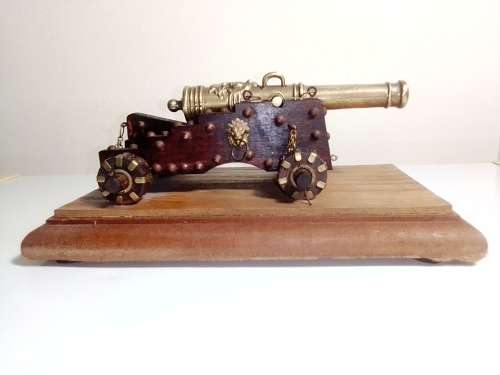 A Brass Canon with crest on Barrel, mounted on a wooden plinth with 4 feet.