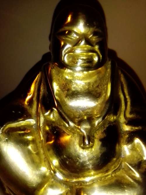 A laughing solid Brass Buddha on white Marble plinth. Symbol of prosperity in Feng Shui.