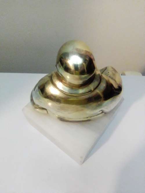A laughing solid Brass Buddha on white Marble plinth. Symbol of prosperity in Feng Shui.
