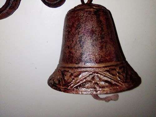 A Old school front door Cast Iron Bell hanging on a nice scrolled bracket.