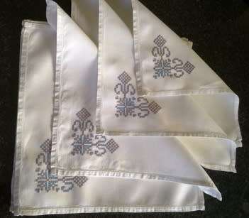 Ten hand embroidered white linen dinner serviettes