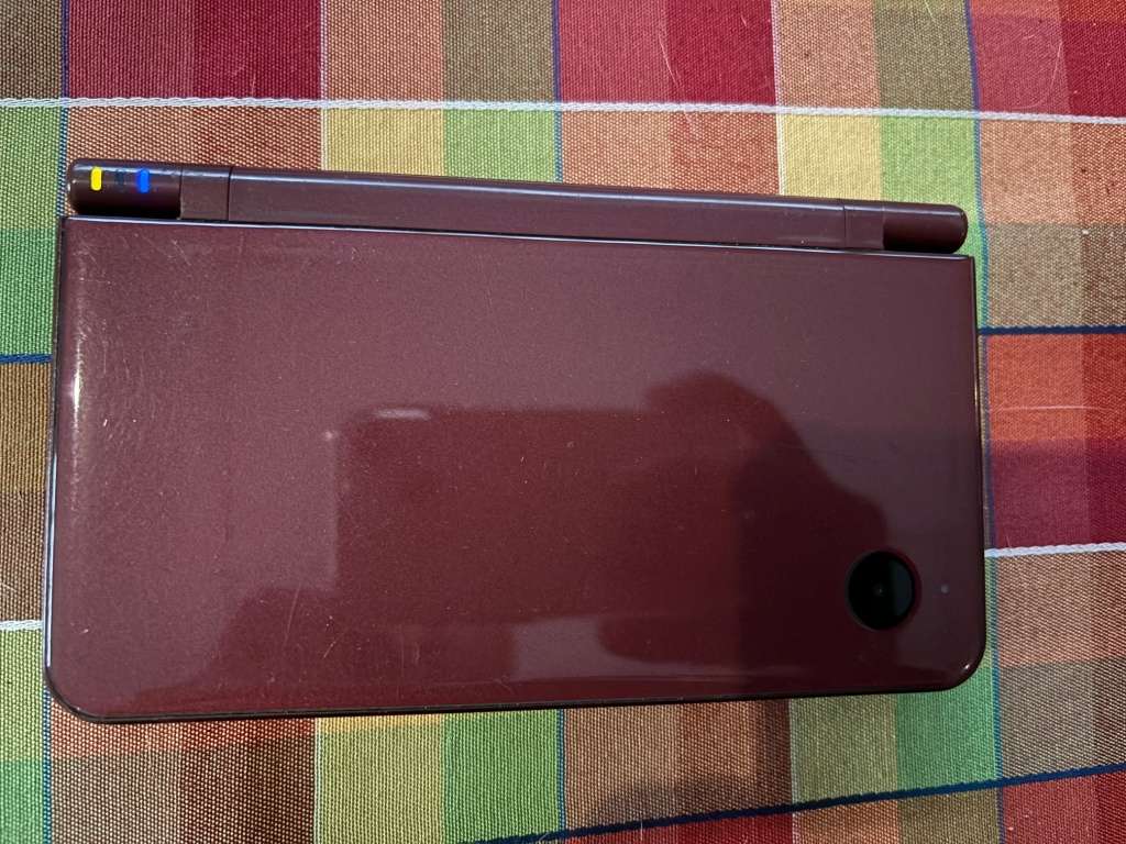 burgundy Nintendo DSi XL with charger