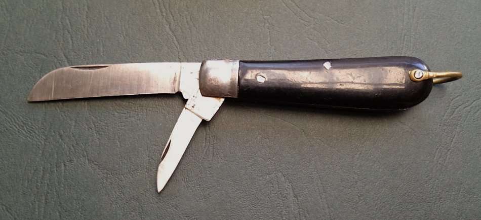 Vintage carbon steel pocket knife, unused in original brown paper wrapping.