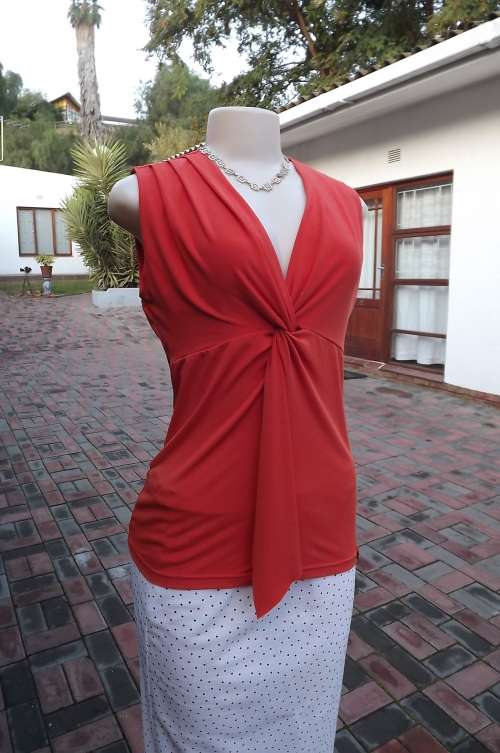 Tangerine colour stretch polyester top by Finnegans. Sleeveless. Size 36/12.Pleats on shoulders