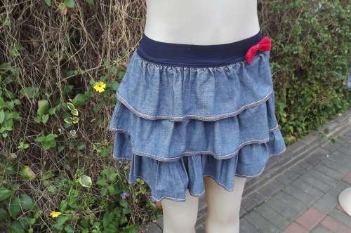 Blue denim multi frilled mini skirt with black elasticated waistband.Size 30/6.Cheeky red bow front