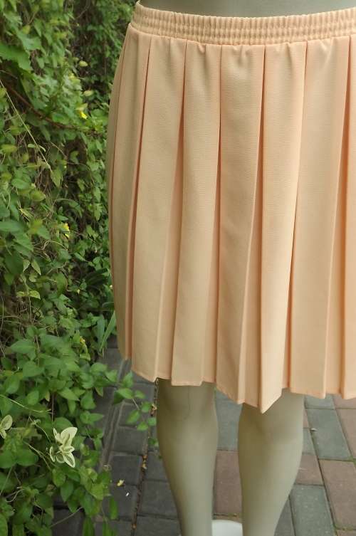 Mini skirt in peach colour by Arezzo in size 32/8 with permanent box pleats.in wash + wear polyester