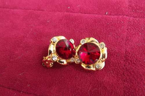 Pair of vintage clip on gold earrings with red inner stones and simulated diamonds at side.